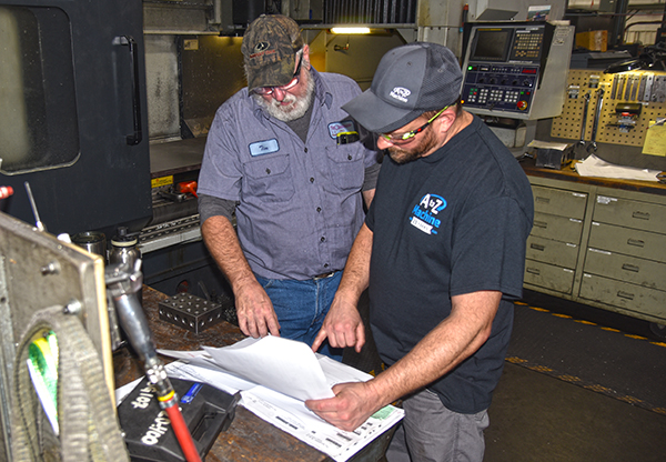 two A to Z Machine employee looking at design plans on a workbench