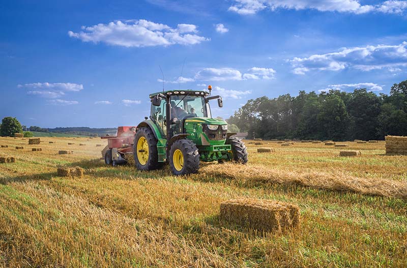 A tractor bailing up hay