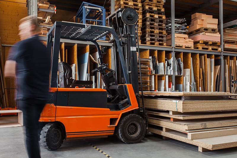 a forklift parked underneath a large stack of wood